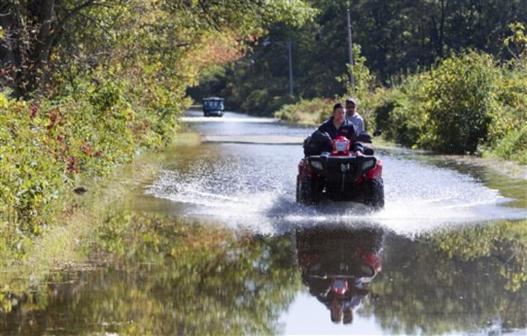 Randy Lloyd, front, and Trevor Hurst drive an all-terrain vehicle out of a flooded area Monday, Sept. 27, 2010, near Portage, Wis. (AP Photo/Andy Manis)